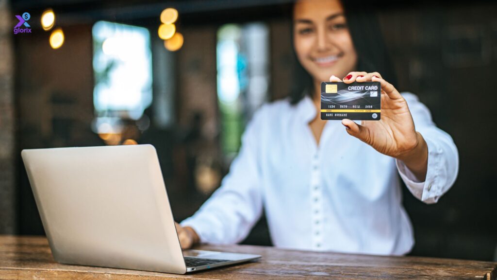 Woman showing a credit card while using a laptop to build a credit score in the USA