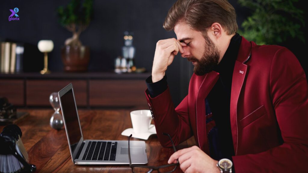 A stressed man sitting at a desk with a laptop, worried about his low credit score in the USA.